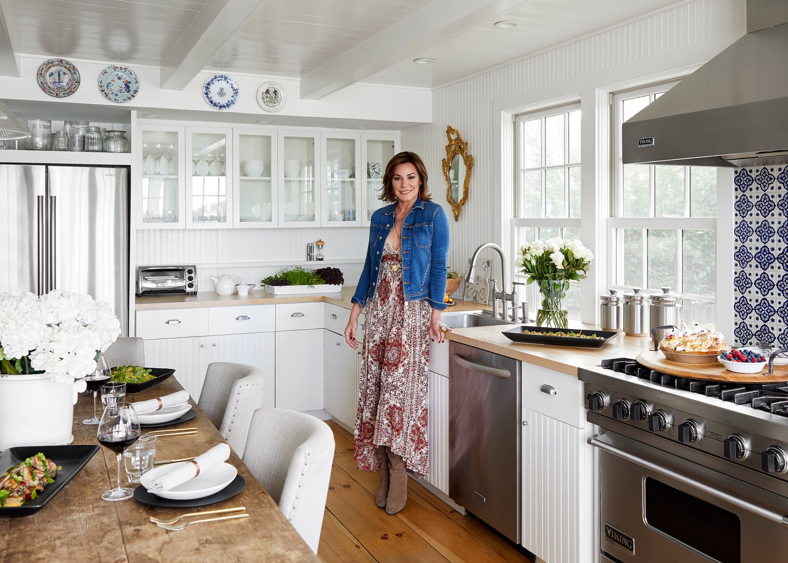 Luann de Lesseps of “The Real Housewives of New York” in whitewalled kitchen with blue patterned backsplash and glass...