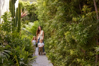 Ariel Kaye with her two young children on a stone pathway cutting through lush greenery