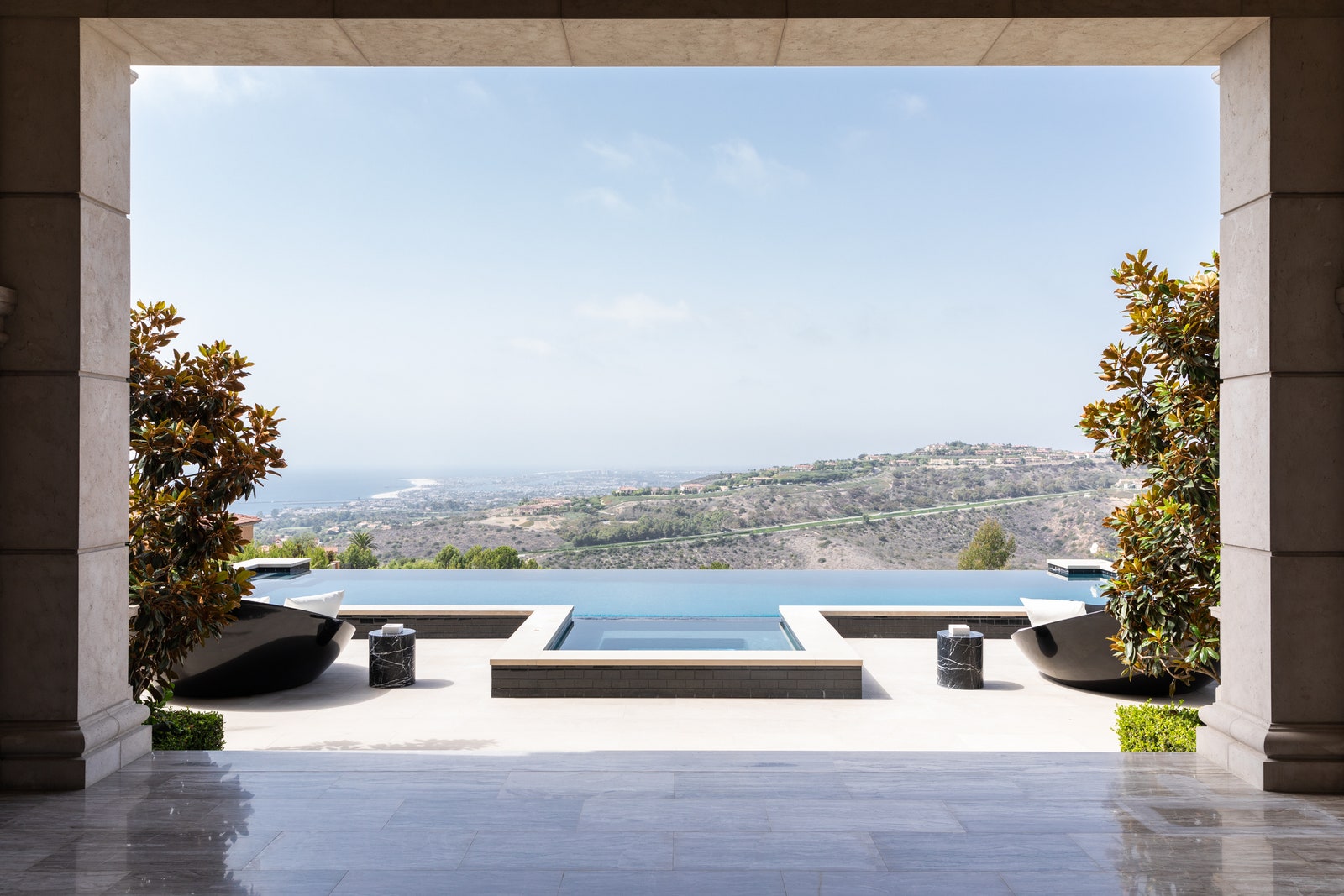 Stone floors large rectangular opening in wall framing a pool with views of the Orange County vista